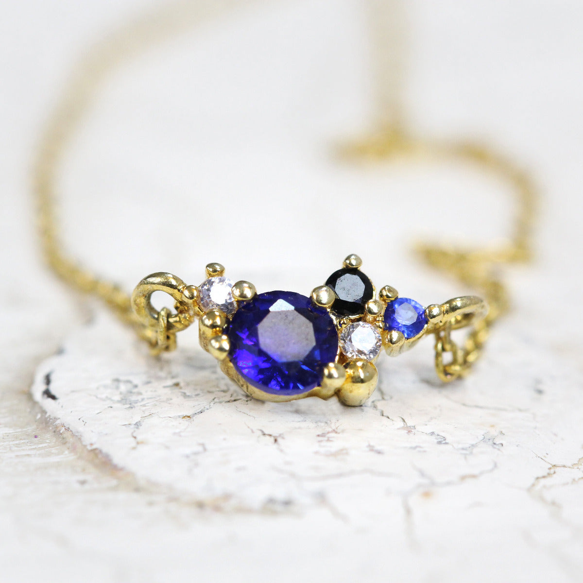 Blue and white crystals set in a gold necklace design that looks like a galaxy or constellation.