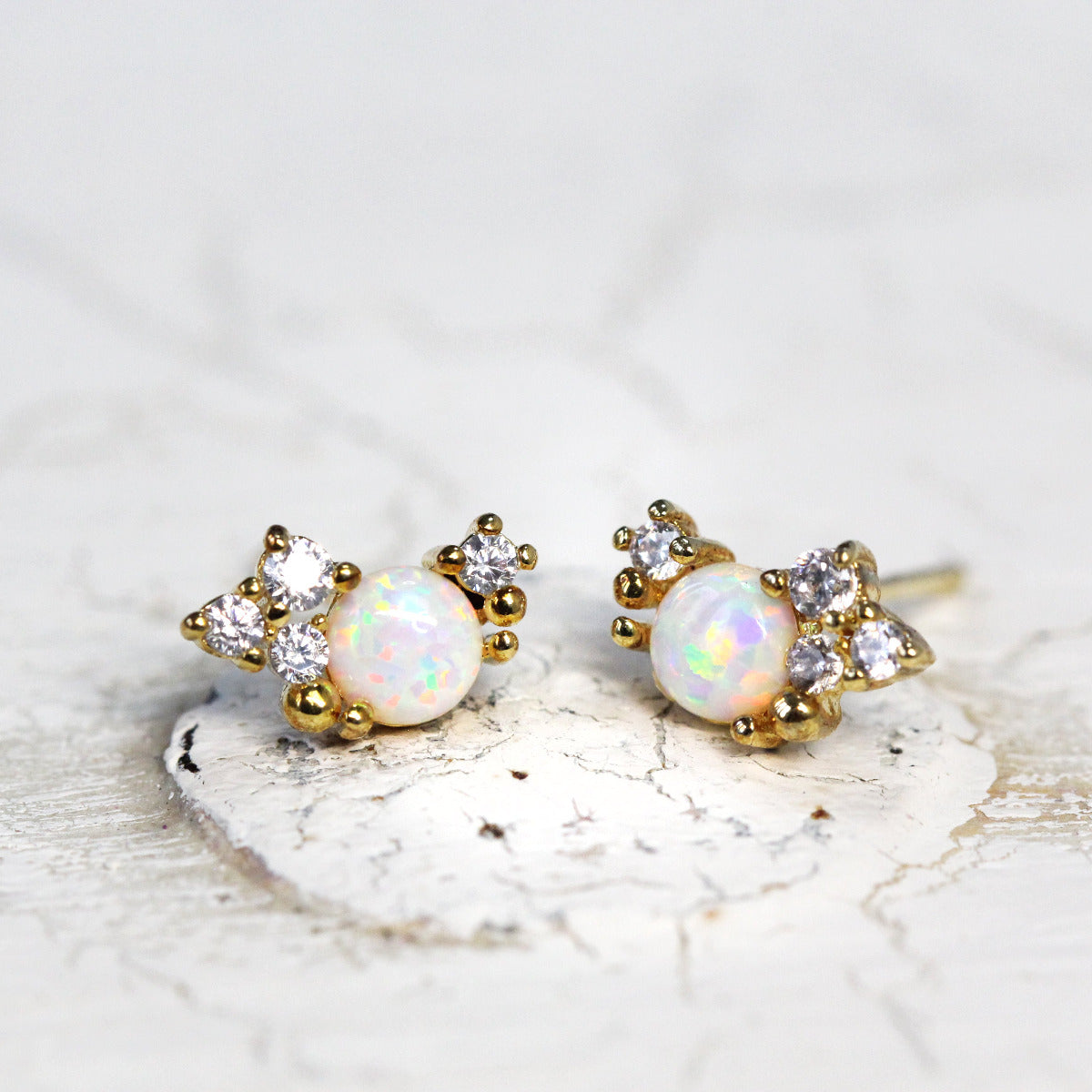 A pair of gold-colored stud earrings featuring a cluster design with sparkling cubic zirconia stones.