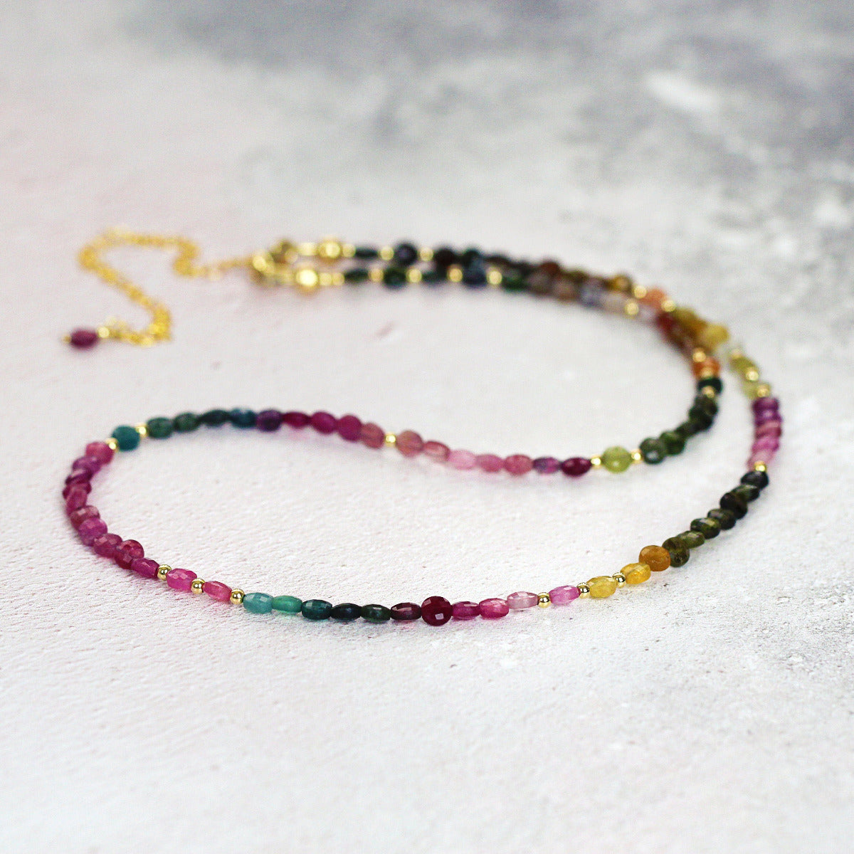 Multicolored tourmaline beaded necklace on a light gray background