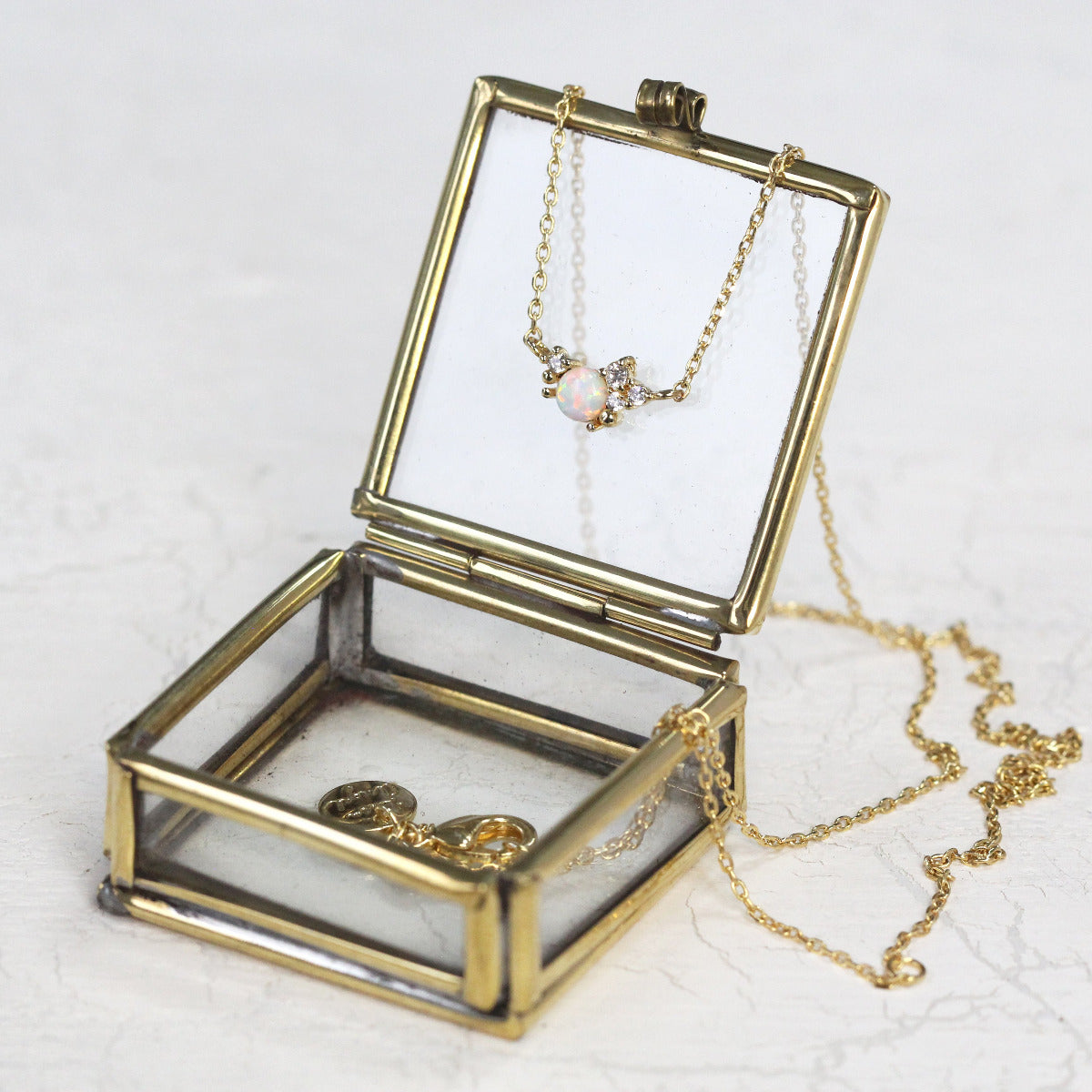 An October Birthstone Crystal Cluster Necklace in Gold displayed on a brass jewellery box.