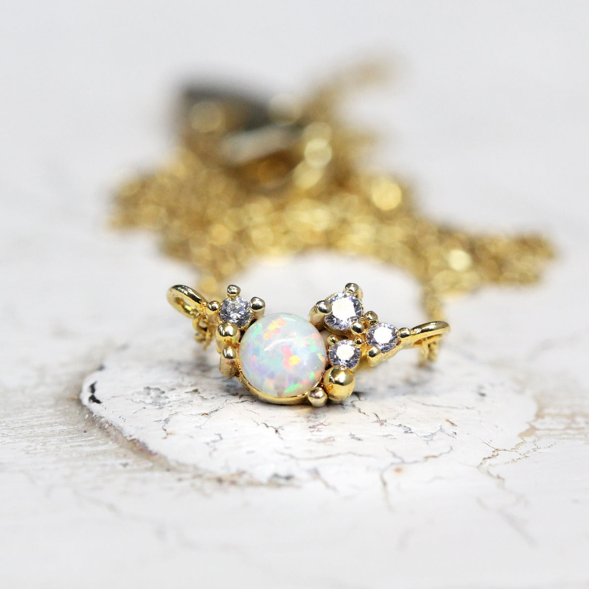 A Cubic Zirconia Crystal and Opal Stone Cluster Necklace with Gold chain shown on a white backkground.