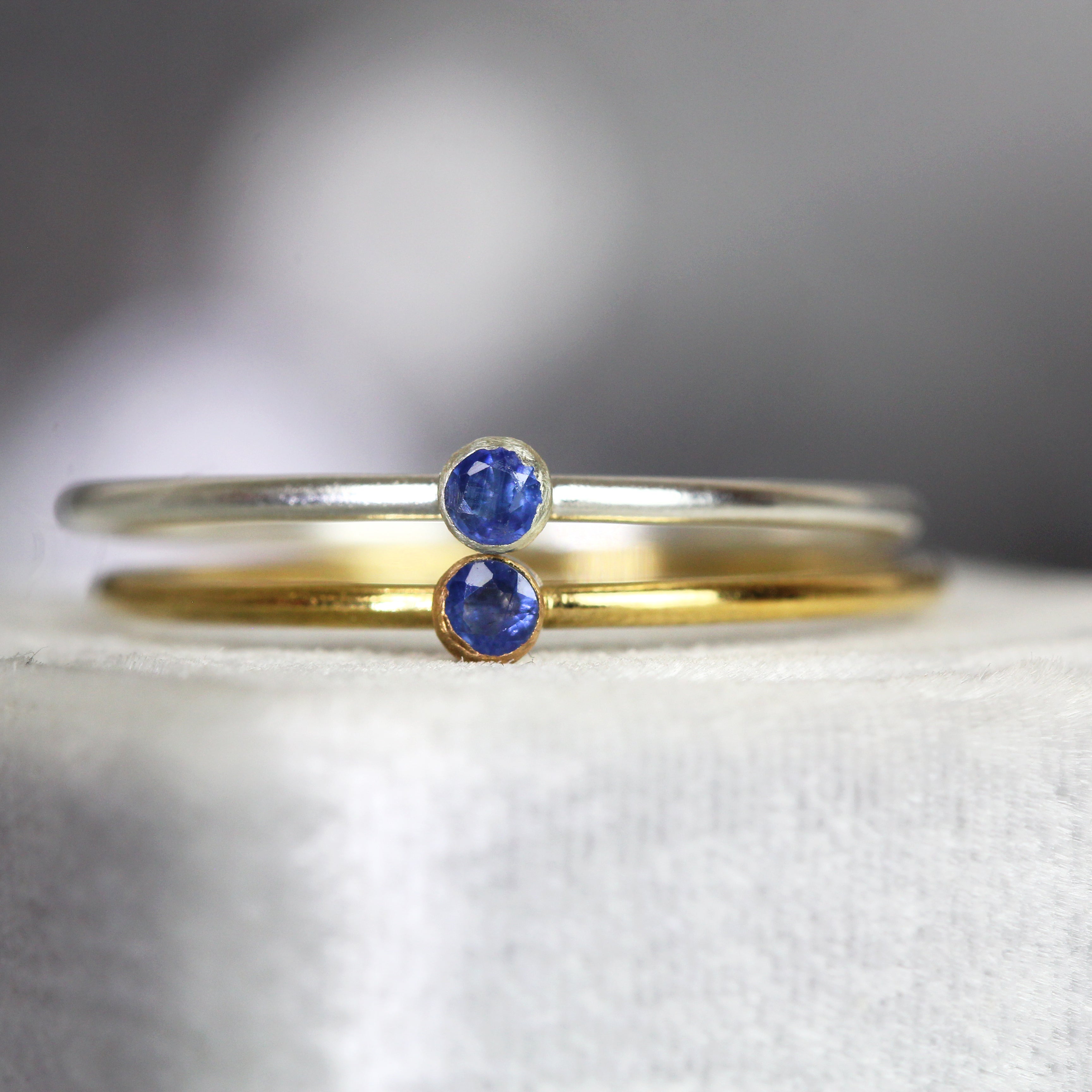 Two rings, one gold and one silver, with blue sapphire gemstones