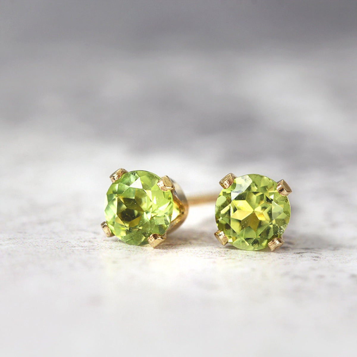 Handmade gold stud earrings featuring faceted bright green peridot gemstones in a prong setting. Round in shape, with ear post fitting and matching butterfly backs. Simple minimal and elegant in style, the earrings also come in various sizes.