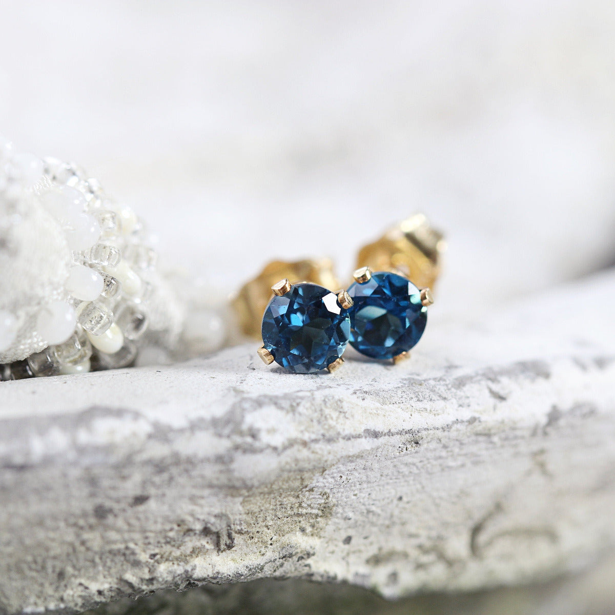 Handmade gold fill stud earrings featuring faceted London Blue topaz gemstones in a prong setting. Round in shape, with ear post fitting and matching butterfly backs. The earrings are simple minimal and elegant in style, and come in various sizes.