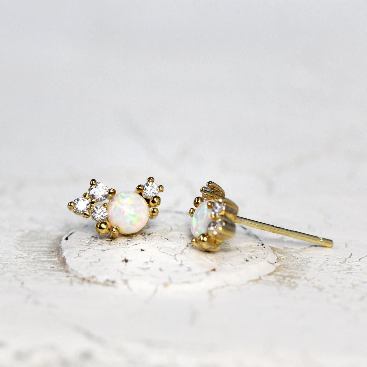 A pair of gold-colored stud earrings featuring a crystal cluster design with sparkling cubic zirconia stones.