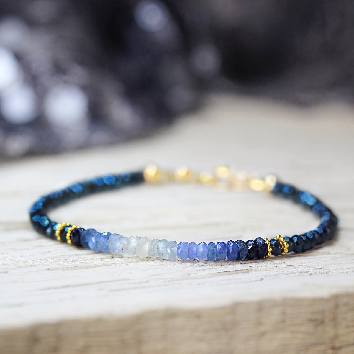 Beaded sapphire bracelet with blue, white, and gold beads on a wooden surface
