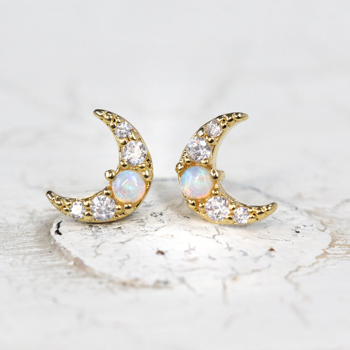 A pair of Opal Crescent Moon Stud earrings in gold displayed on a white background
