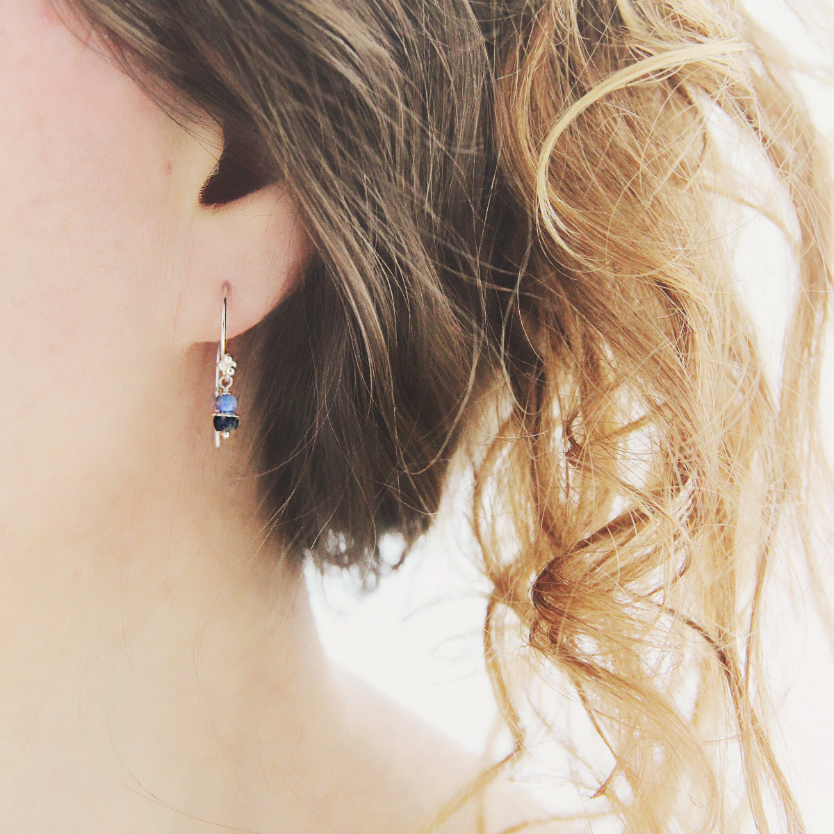 Silver Sapphire Drop Earrings worn by a person with wavy hair