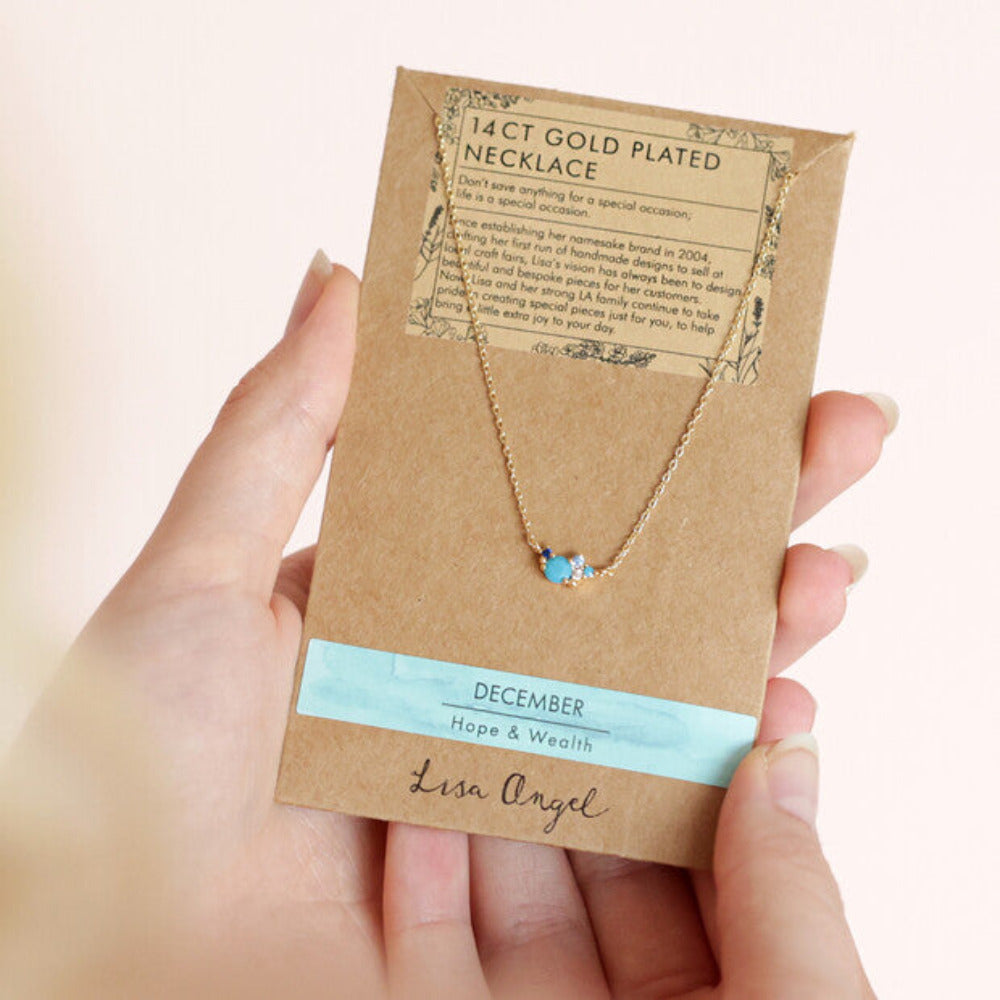 A crystal cluster necklace dispayed on a gift card that is held in a hand.