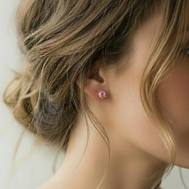 Close-up of a person wearing pink stud earrings with a blurred background