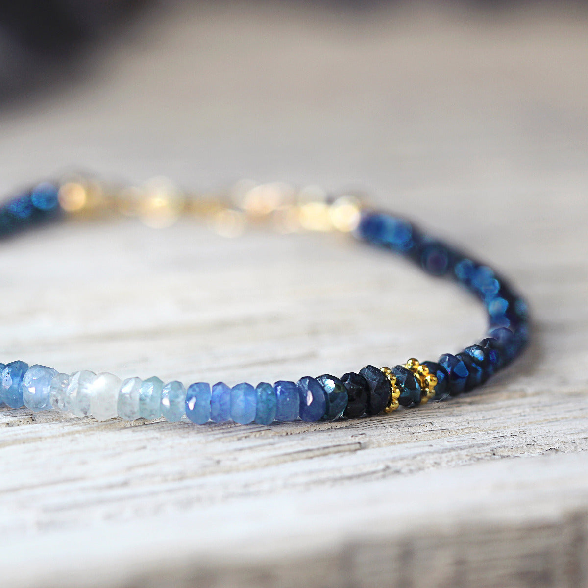 Close up of beaded sapphire bracelet with blue and gold beads on a wooden surface