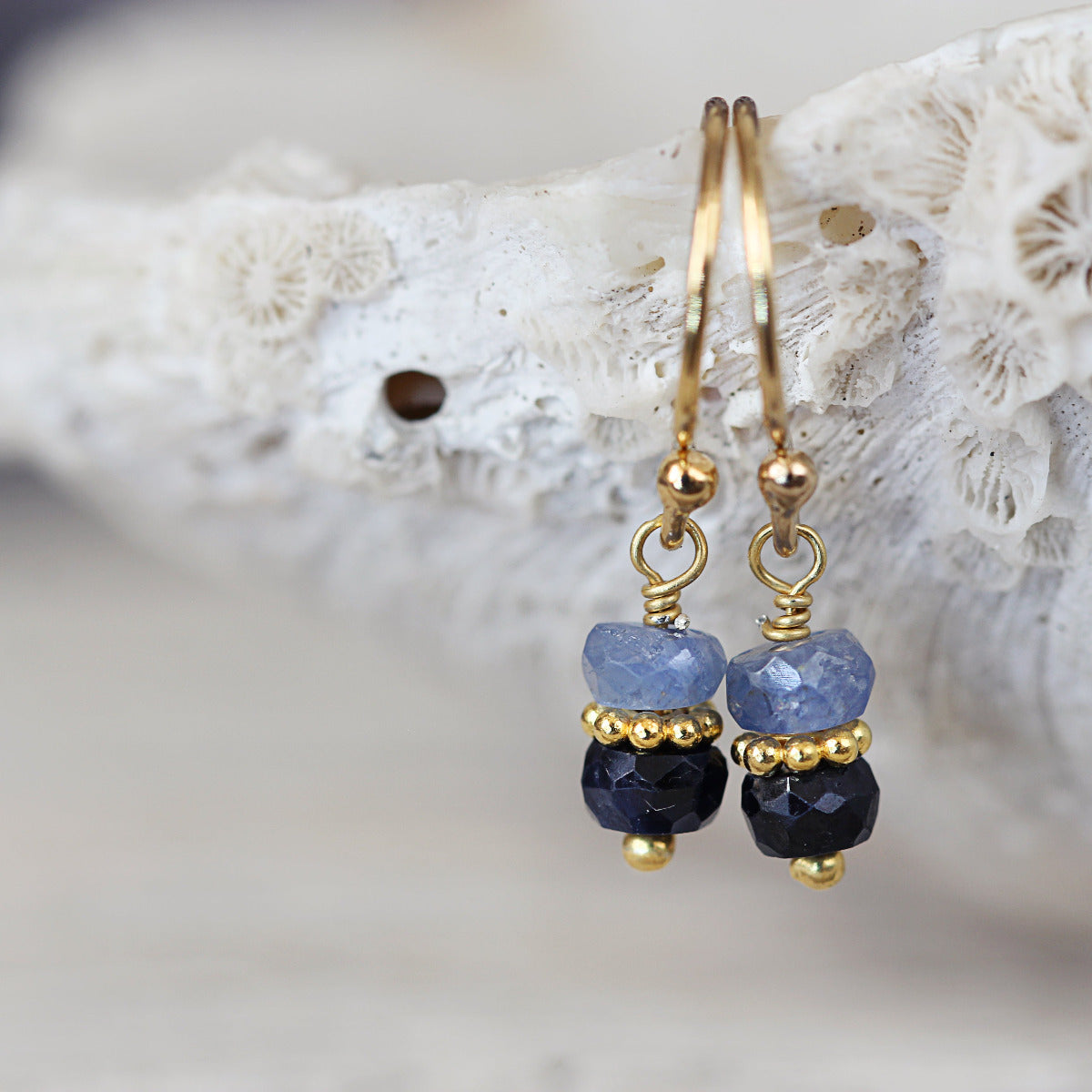 Gold and blue sapphire beaded earrings on a white coral background