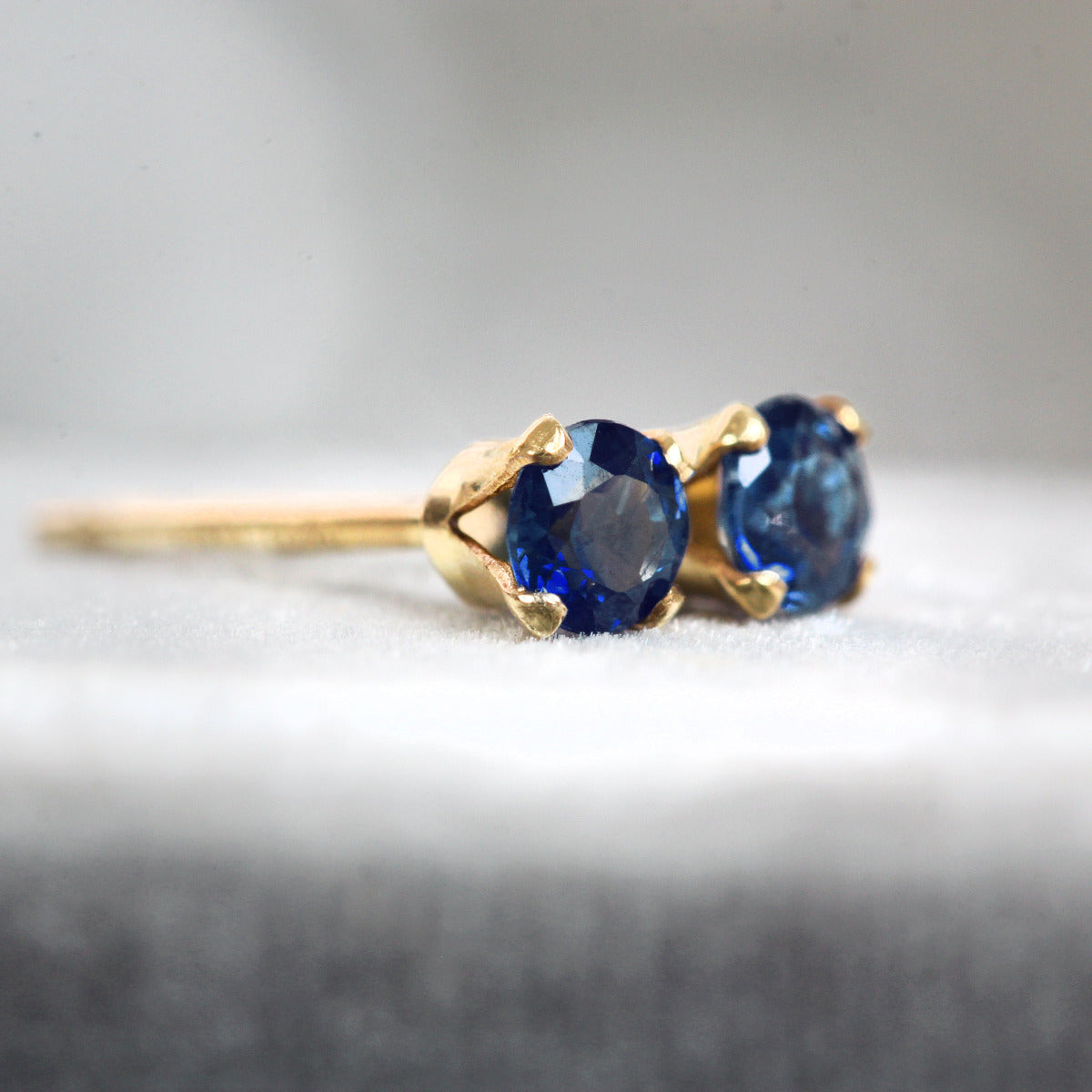 Gold earrings with sparkling blue sapphire gemstones on a gray background