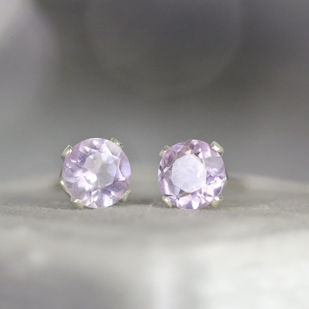 A pair of silver stud earrings featuring faceted lavender amethyst gemstones in a prong setting. Round in shape, with ear post fitting and matching butterfly backs. Simple, sophisticated and minimal in style, available in various sizes.
