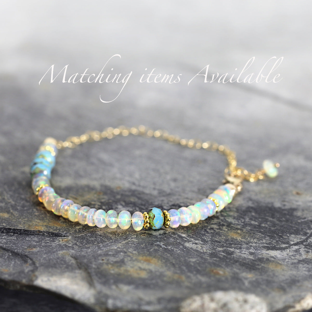 Opal beaded bracelet with gold chain on a gray stone surface with text 'Matching items Available'.