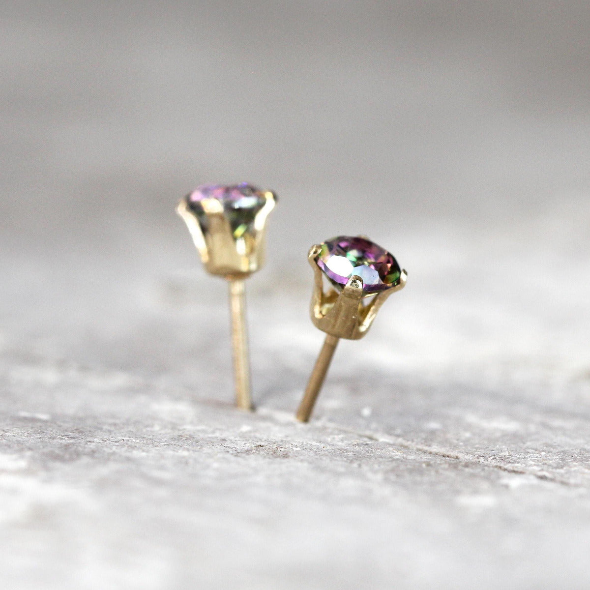 Gemstone stud earrings showcasing mystic topaz stones set into 14k gold fill ear posts. The topaz gemstones are a brilliant round cut and are colourful, dazzling and sparkling. The ear posts are gold filled four prong settings with push backs.