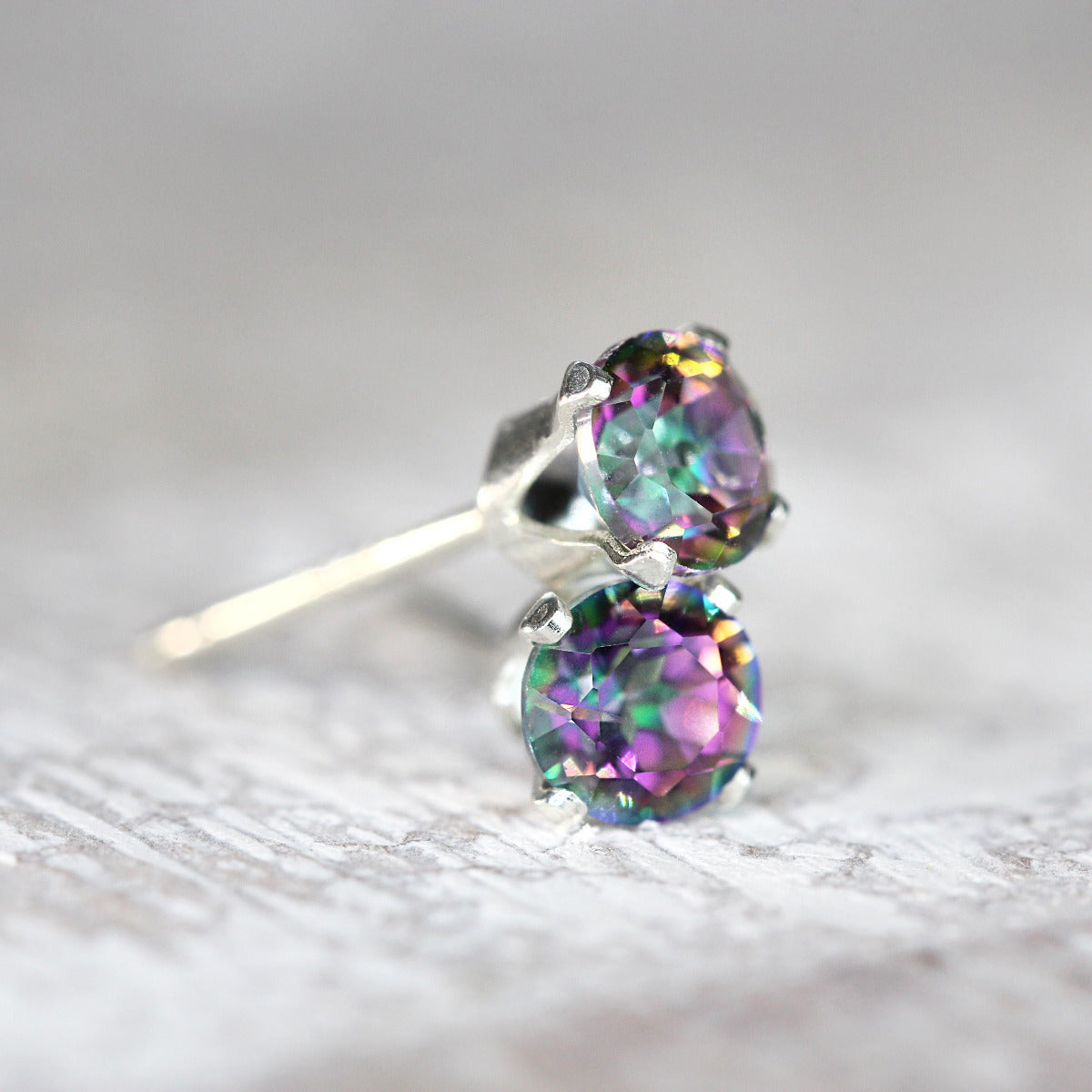 One pair of simple, minimal stud earrings featuring mystic topaz. The mystic topaz gemstones are a brilliant round cut with lots of sparkling facets, and peacock colour effect. They are set into sterling silver prong settings with a post fitting.