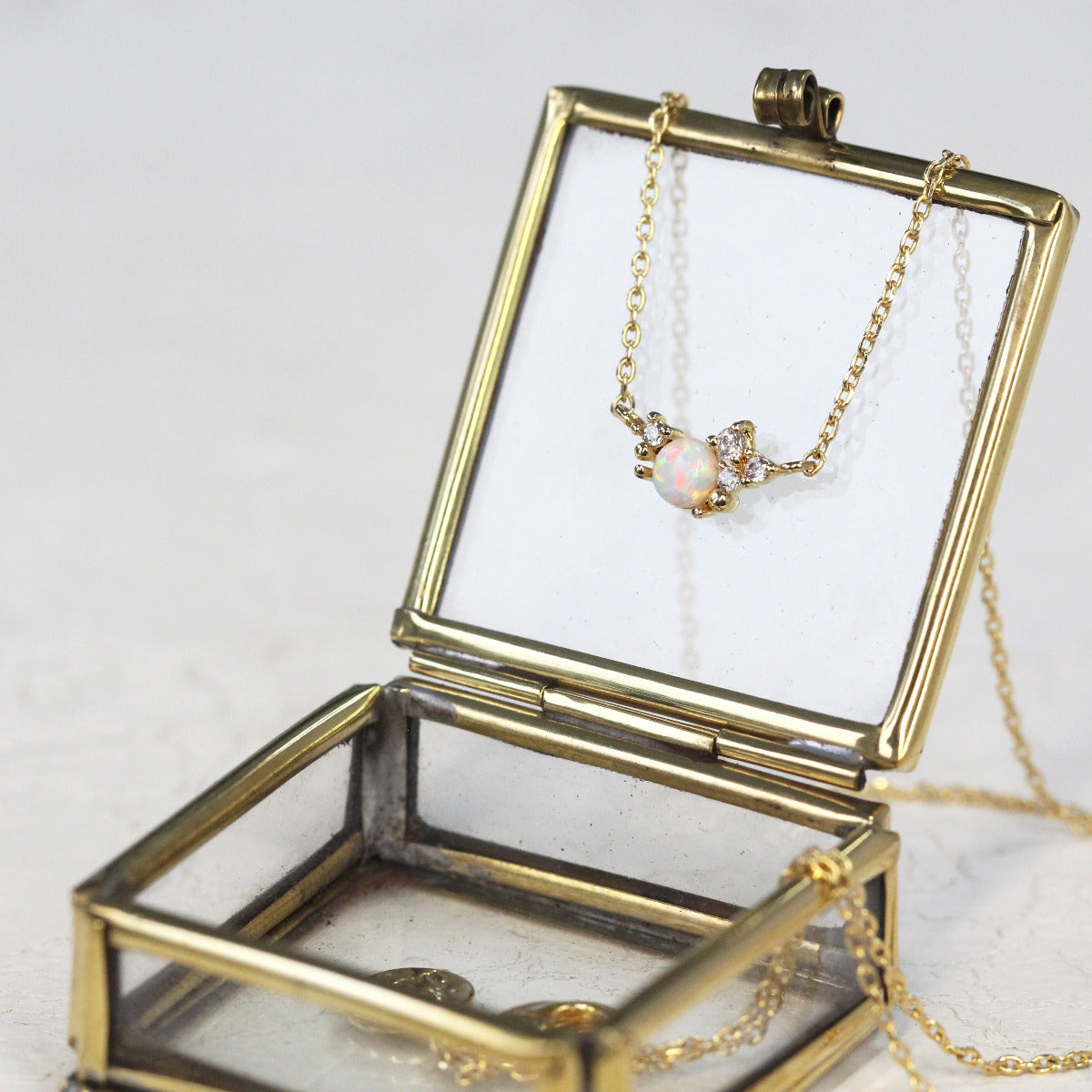 An October Birthstone Crystal Cluster Necklace in Gold displayed on a brass jewellery box.