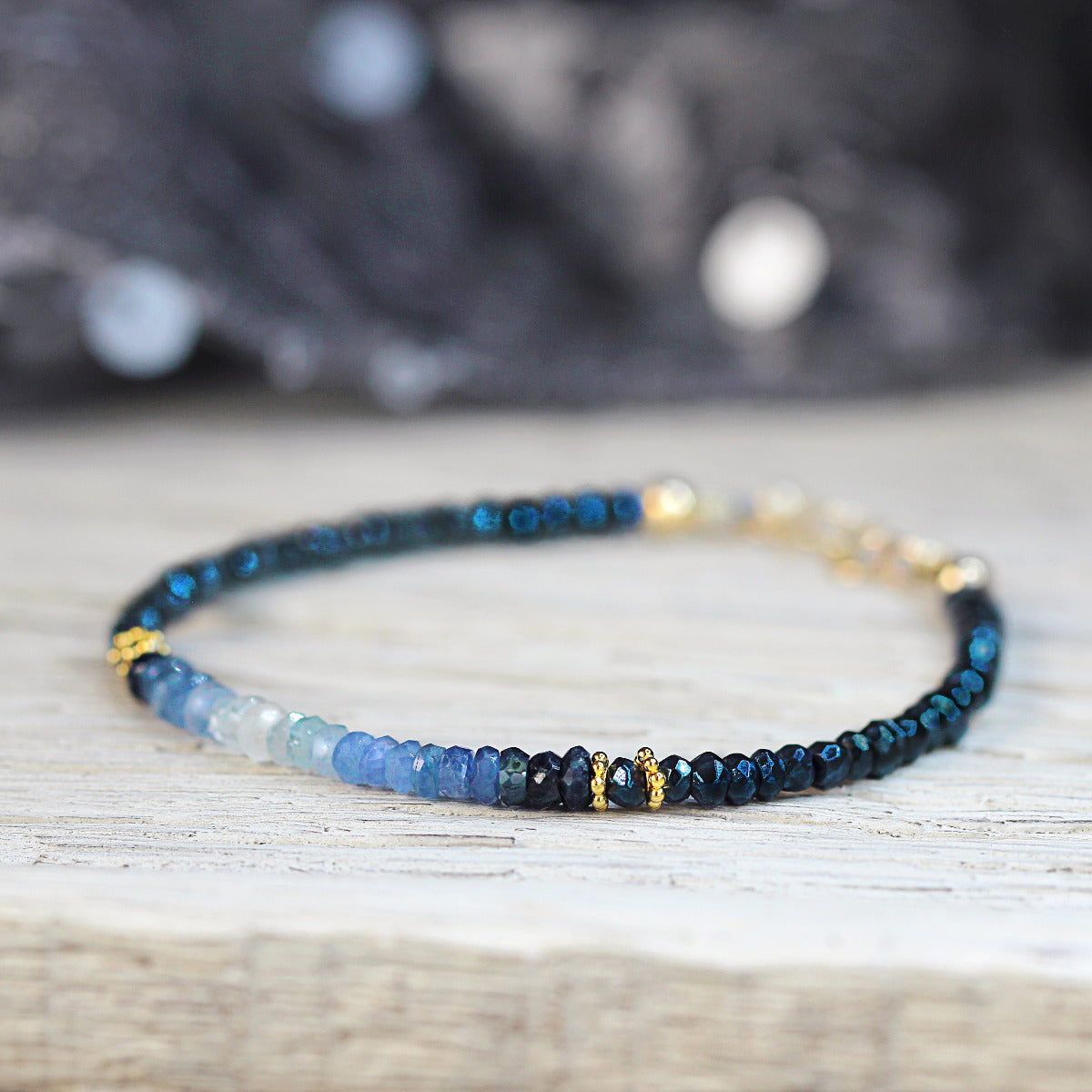Blue beaded sapphire bracelet with gold accents on a wooden surface