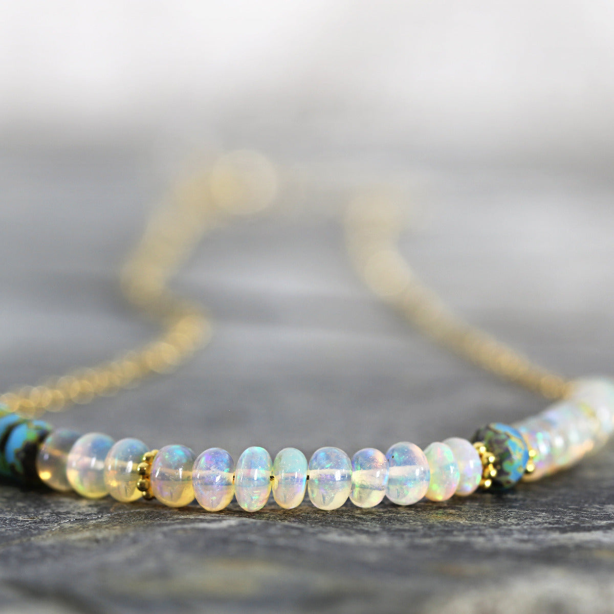 Opal beaded necklace with gold chain on a neutral background