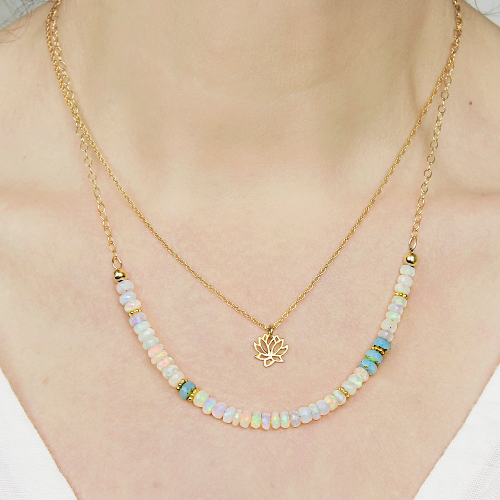 Beaded necklace with opal beads and a gold chain on a person wearing a white top.