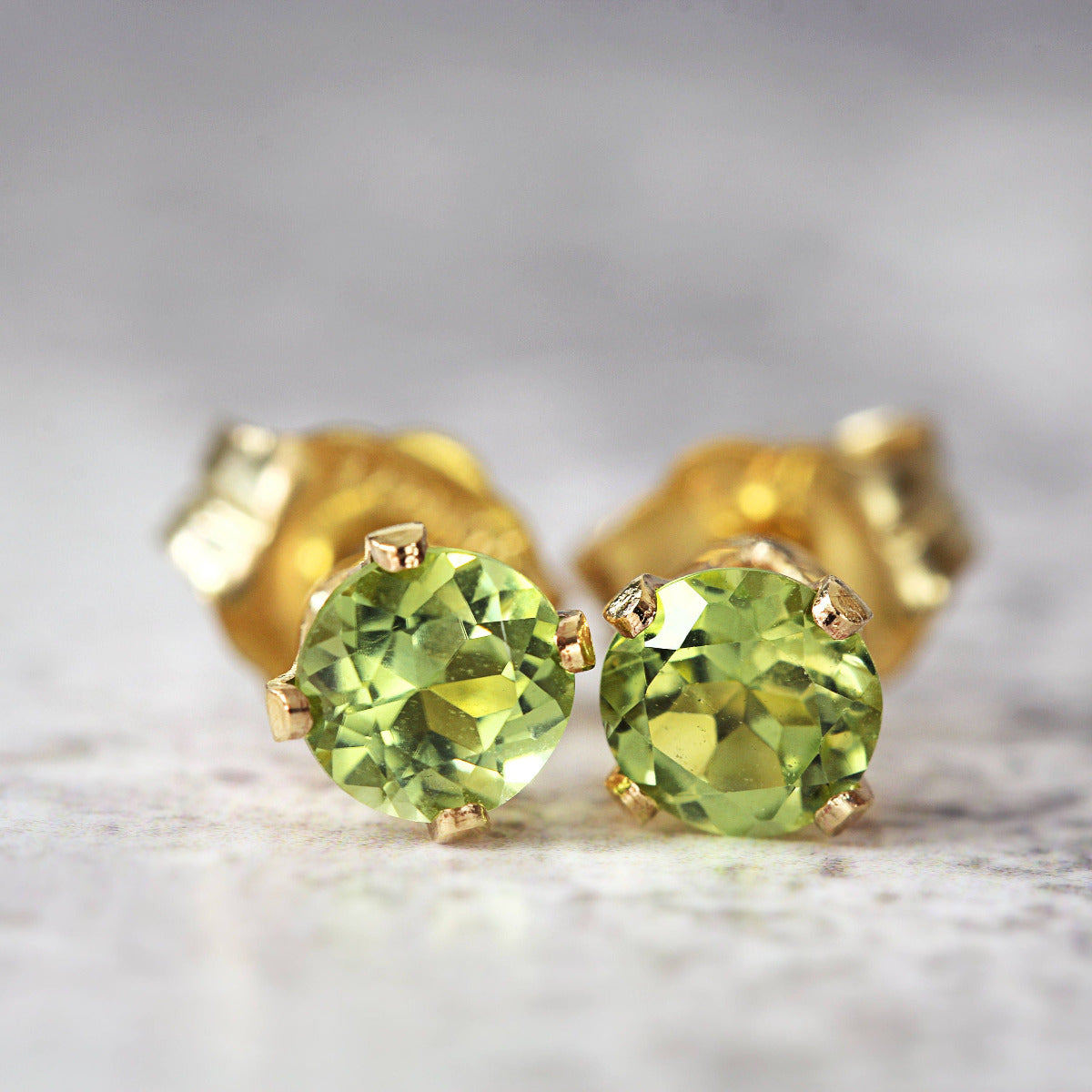 Handmade gold fill stud earrings featuring faceted bright green peridot gemstones in a prong setting. Round in shape, with ear post fitting and matching butterfly backs. The earrings are simple minimal and elegant in style, and come in various sizes.