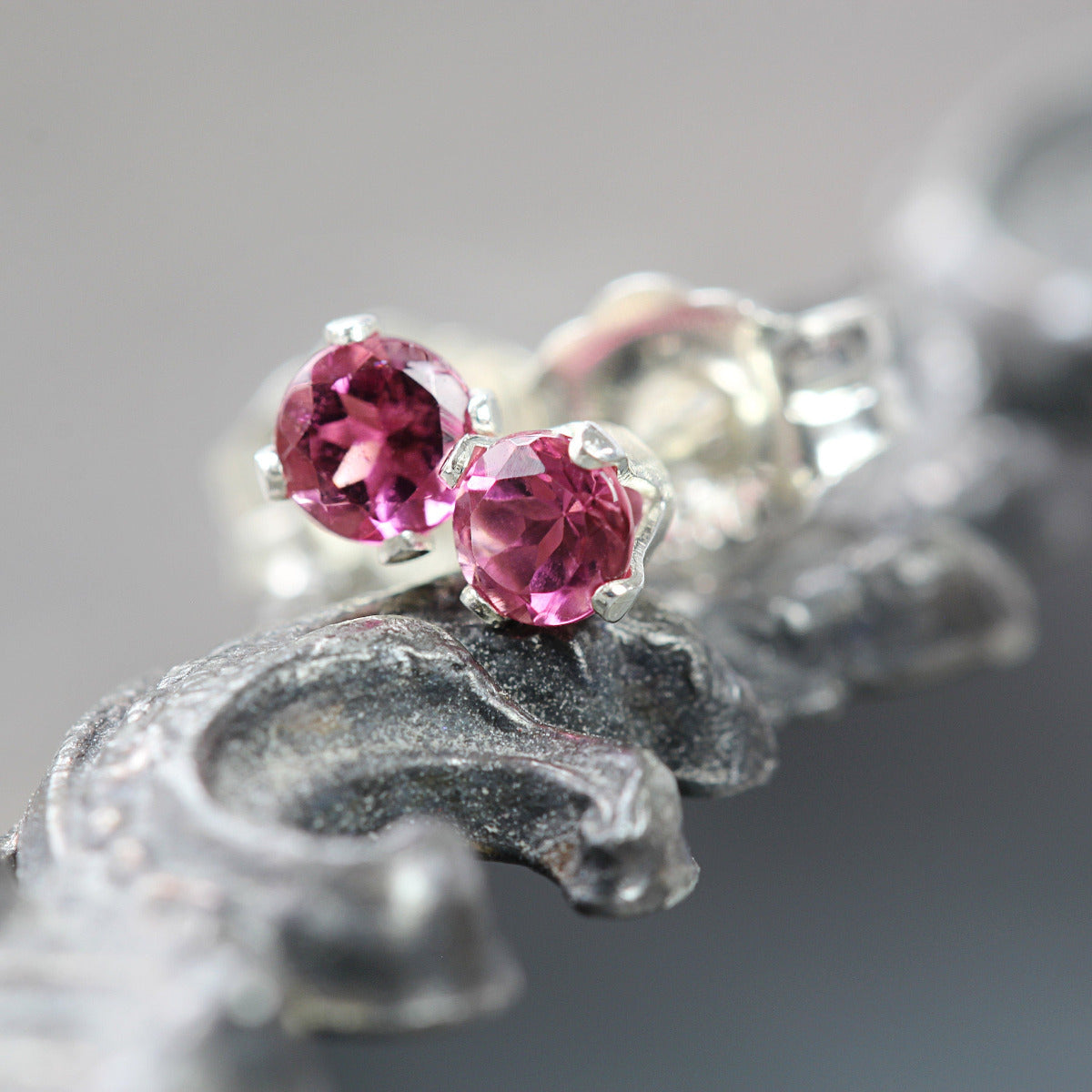 A pair of silver stud earrings featuring faceted, rose pink tourmaline gemstones in a prong setting. Round in shape, with ear post fitting and matching butterfly backs. The earrings are simple, sophisticated and minimal and come in various sizes.