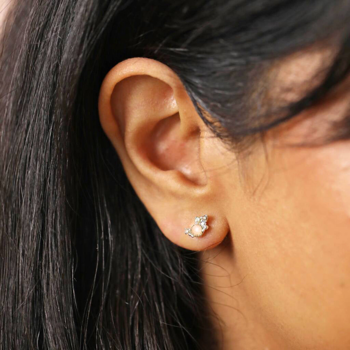 A close up of an ear wearing a crystal cluster stud earring in gold and silver