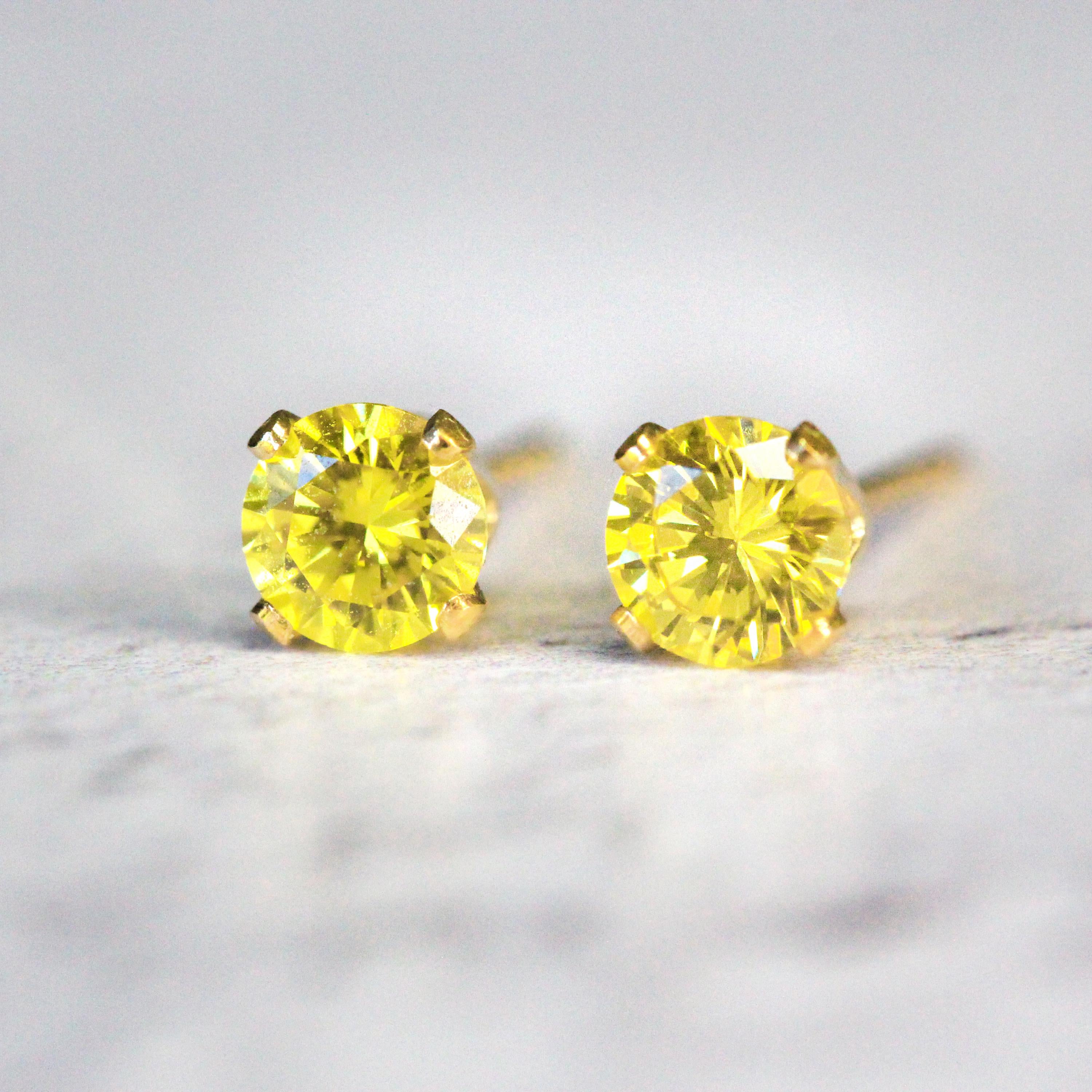 Yellow stud earrings featuring a faceted round cubic zirconia gemstones. The sparkling cz stones are set into a 4 prong gold setting. The studs are round in shape with ear post fitting matching butterfly backs. The earrings are simple and minimal in style. Various sizes available.