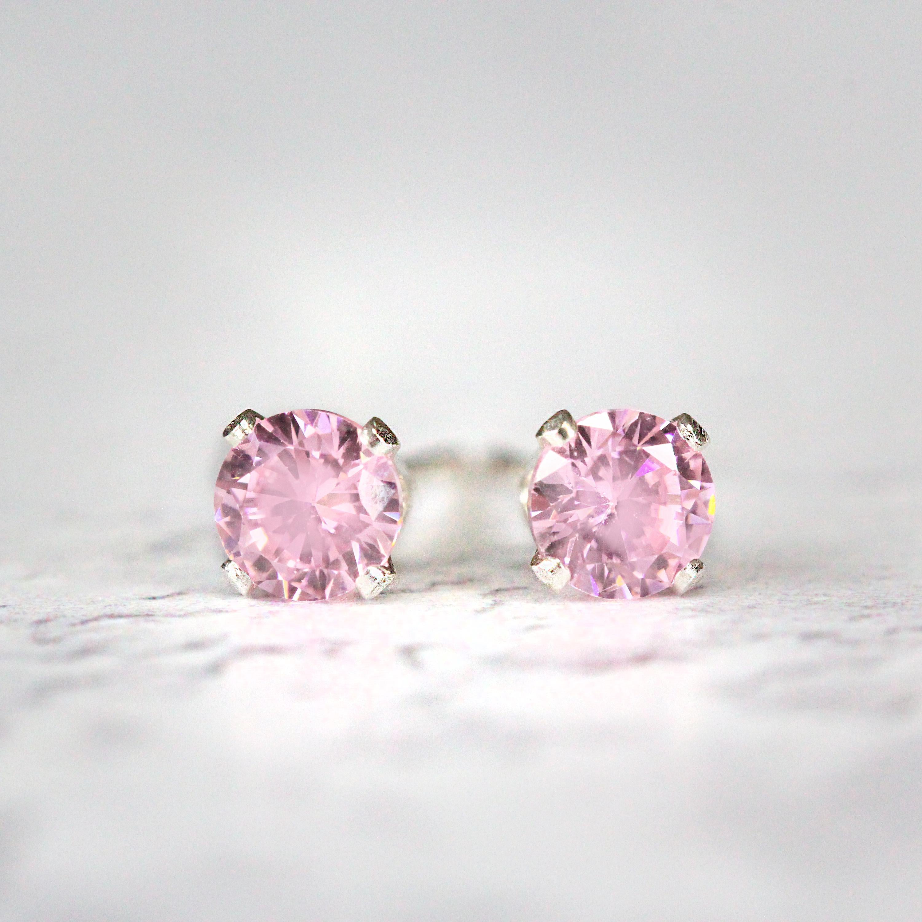 Pink stud earrings featuring a faceted round cubic zirconia gemstones. The sparkling cz stones are set into a 4 prong sterling silver setting. The studs are round in shape with ear post fitting matching butterfly backs. The earrings are simple and minimal in style. Various sizes available.