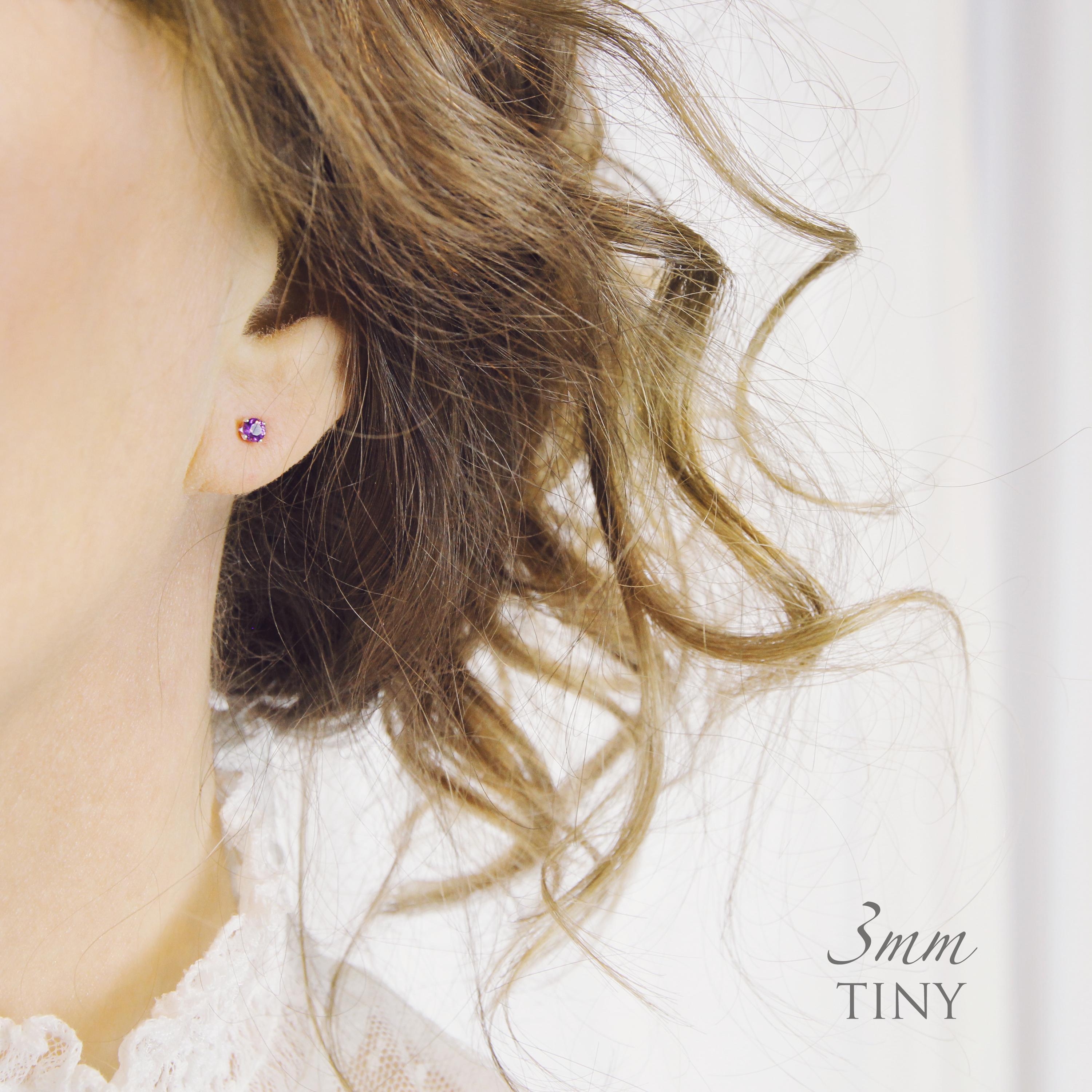 A model wears a tiny 3mm round stud earring with gemstone to show the size and scale of stud earrings.