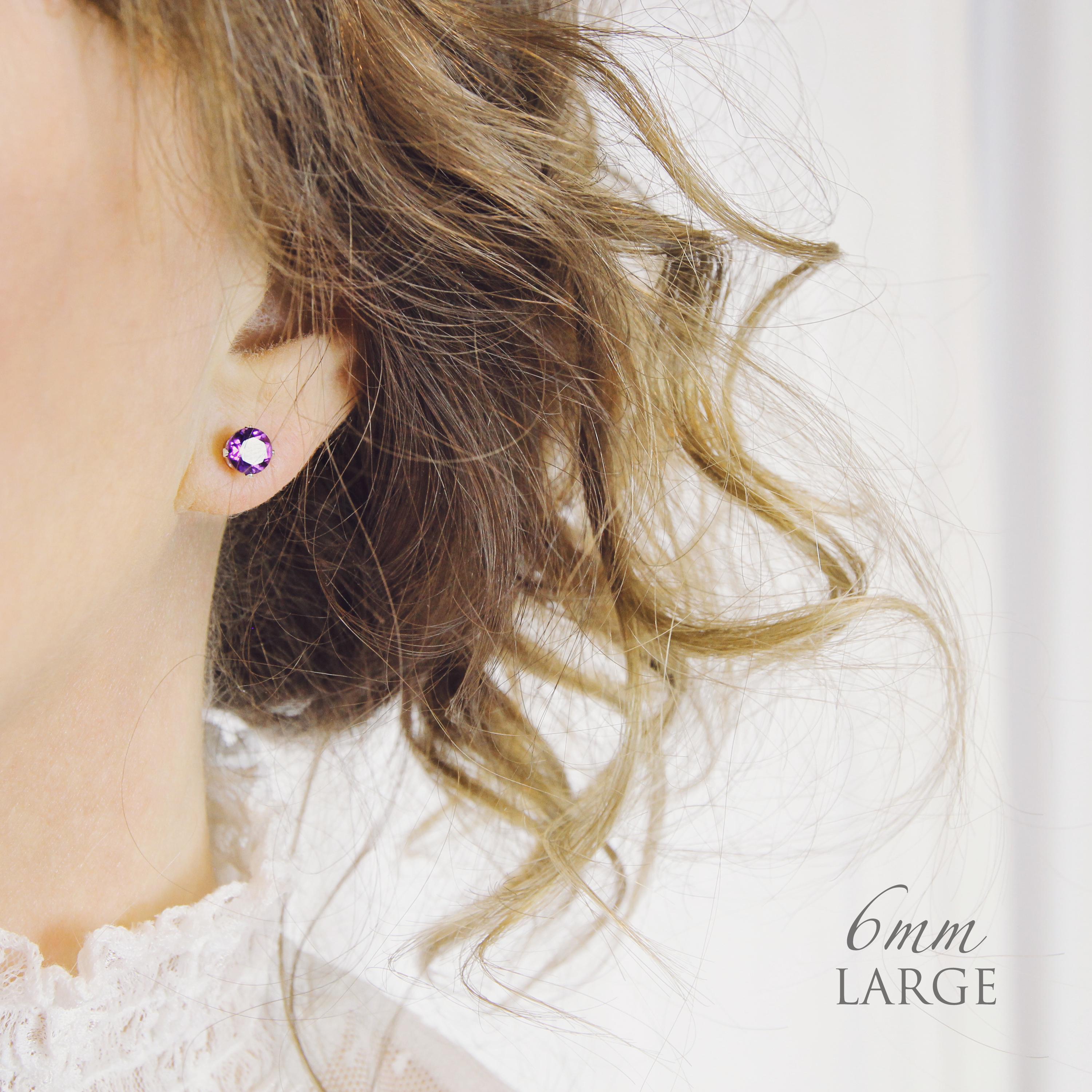 A model wears a large statement 6mm round stud earring with gemstone to show the size and scale of stud earrings.