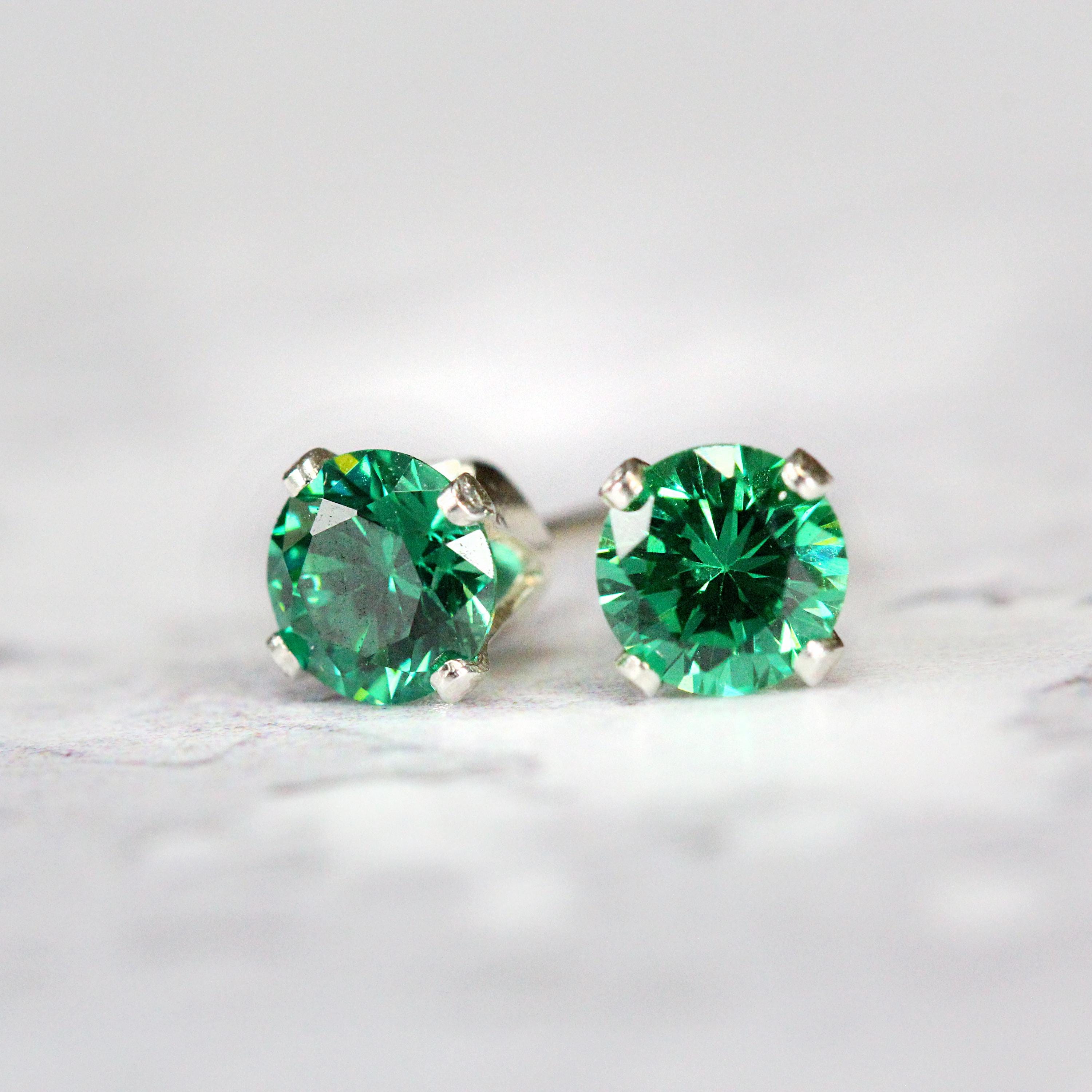 Teal Green stud earrings featuring a faceted round cubic zirconia stone. The sparkling crystal cz stones are set into a 4 prong gold setting. These colourful crystal earrings are round in shape with ear post fitting matching butterfly backs. They are simple and minimal in style. Various sizes available.